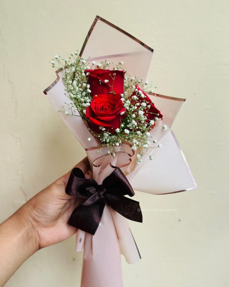 Three red rose bouquet wrapped in white 'LOVE' paper and a red ribbon.