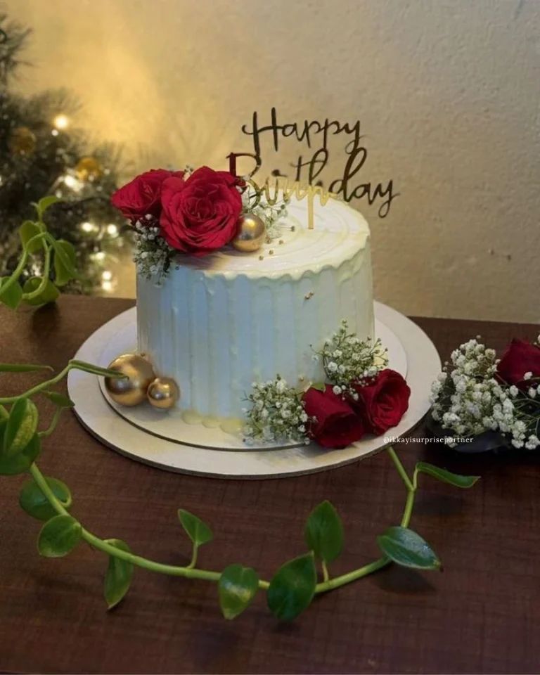 Luxury white birthday cake decorated with fresh red roses and gold accents.