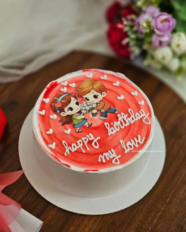 White and red birthday cake with a cartoon couple, 'happy birthday my love' message, and heart accents.