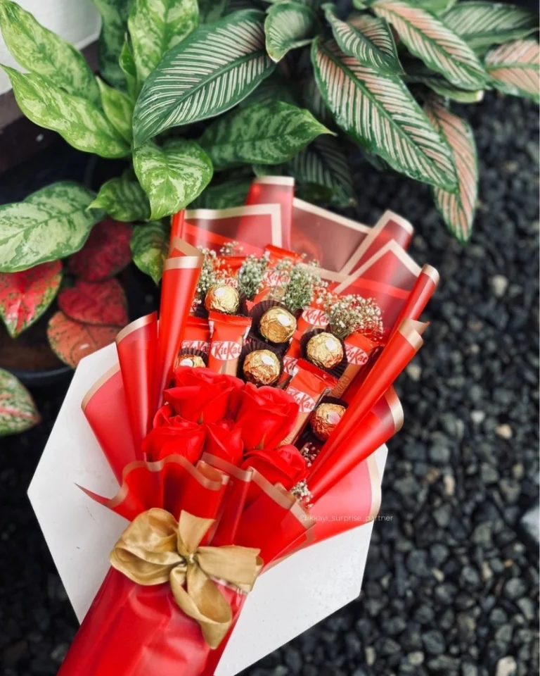 Red rose and chocolate bouquet with KitKat and Ferrero Rocher, wrapped in red and gold paper.