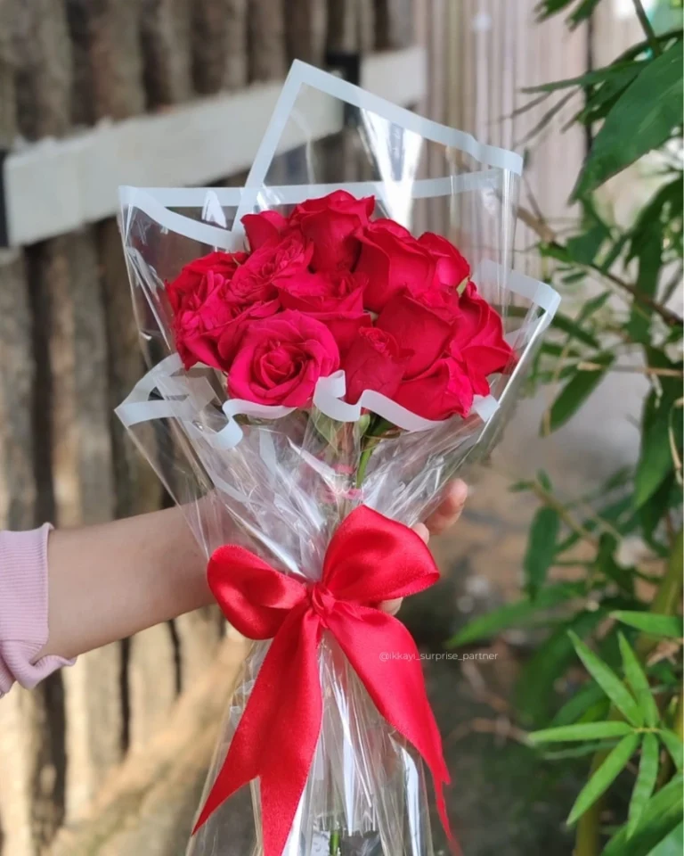Seven red rose bouquet wrapped in clear cellophane with a red ribbon.